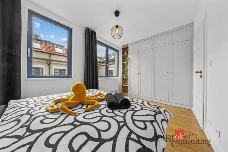 Moderný 2i apartmán v novostavbe v Starom Meste - Spálňa v 2-izbovom byte s veľkými oknami, vstavanou skriňou a podlahou s dreveným dekorom.