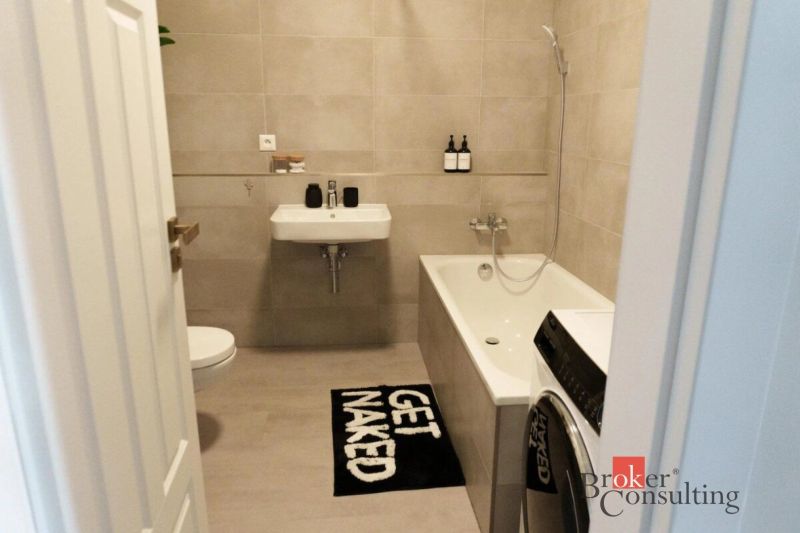 Moderný 2i apartmán v novostavbe v Starom Meste - Kúpeľňa v 2-izbovom byte s vaňou, práčkou a béžovým obkladom.