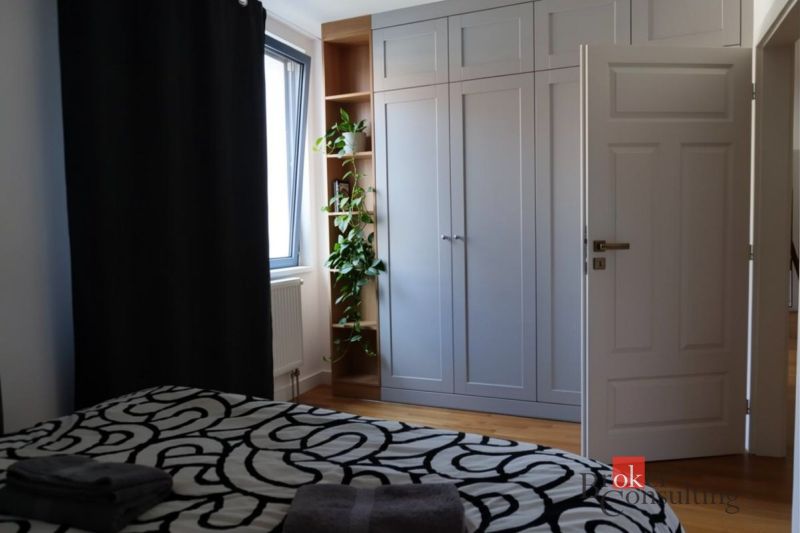 Moderný 2i apartmán v novostavbe v Starom Meste - Spálňa s podlahou s dreveným dekorom, vstavanou skriňou a izbovou rastlinou v 2-izbovom byte.