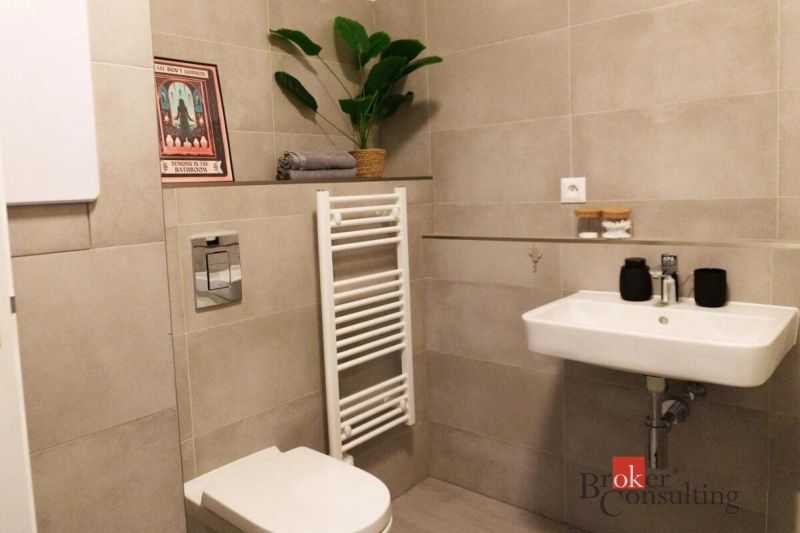 Moderný 2i apartmán v novostavbe v Starom Meste - Kúpeľňa v 2-izbovom byte s béžovým obkladom, umývadlom a toaletou.