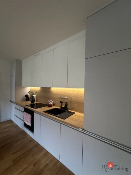 Moderný 2i apartmán v novostavbe v Starom Meste - Kuchyňa v 2-izbovom byte s bielymi skrinkami a podlahou s dreveným dekorom.