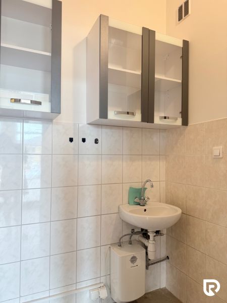 Prenájom 148,25 m² showroom, predajňa | Zlatovce - Umývadlo s batériou pod závesnými skriňami a elektrickým ohrievačom v obchodných priestoroch.