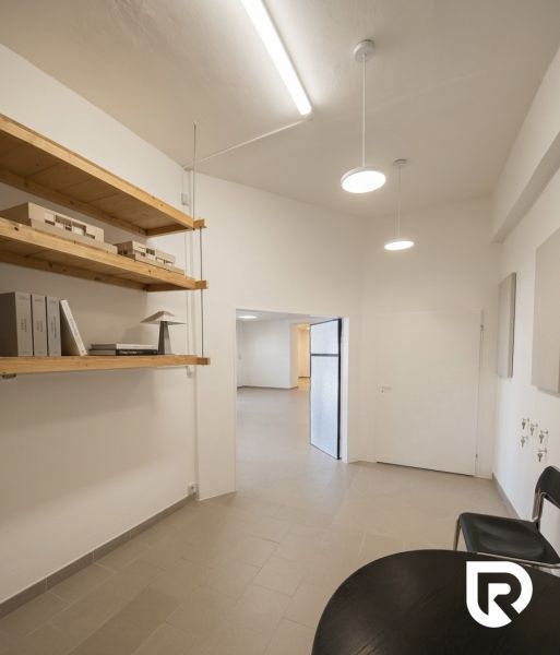 Prenájom 148,25 m² showroom, predajňa | Zlatovce - Svetlý interiér obchodných priestorov s regálom v rohu a jednoduchým osvetlením.