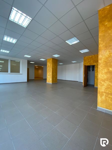 Prenájom 148,25 m² showroom, predajňa | Zlatovce - Interiér obchodných priestorov s dlažbou a oranžovými stĺpmi.