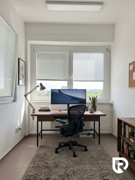 Prenájom 148,25 m² showroom, predajňa | Zlatovce - Kancelársky priestor s pracovným stolom, stoličkou, počítačom, kobercom a policou s knihami.