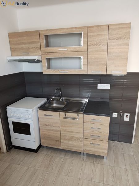 1 izbový byt s balkónom na prenájom  - Kompaktná kuchynská linka s dreveným dekorom v 1-izbovom byte.