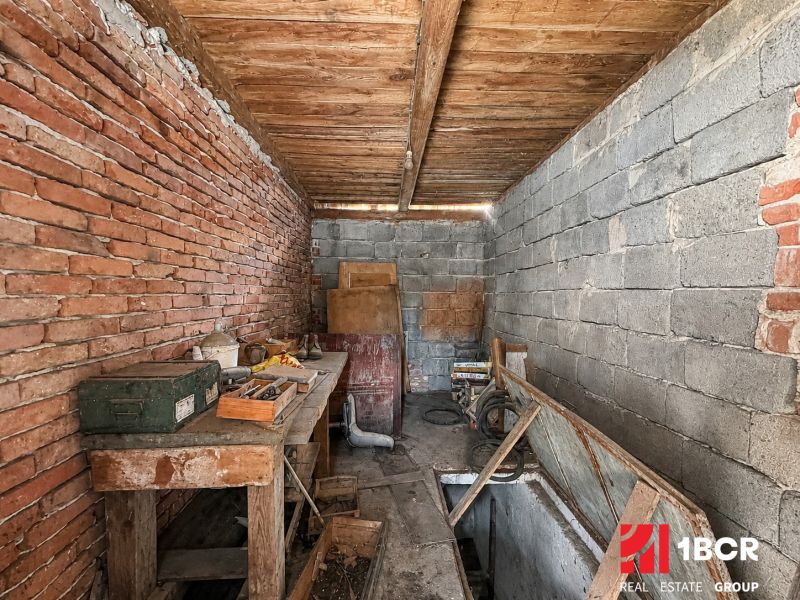 1.BCR | DOM S VEĽKÝM POZEMKOM A POTENCIÁLOM | SOLOŠNICA  - Dielňa v rodinnom dome s pracovným stolom a tehlovou stenou.