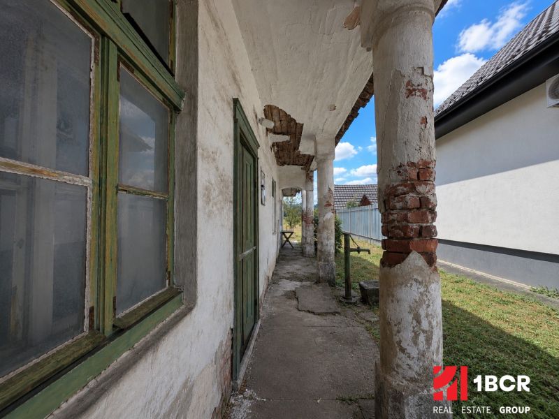 1.BCR | DOM S VEĽKÝM POZEMKOM A POTENCIÁLOM | SOLOŠNICA  - Rodinný dom na ulici Hoštáky v Sološnici s opotrebovanou fasádou a stĺporadím.