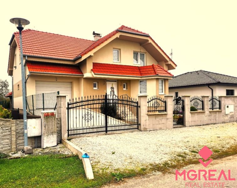6 - izbový rodinný dom v obci Ratkovce, novostavba - Rodinný dom v Ratkovciach s červenou strechou, plotom a spevneným dvorom z kamienkov.