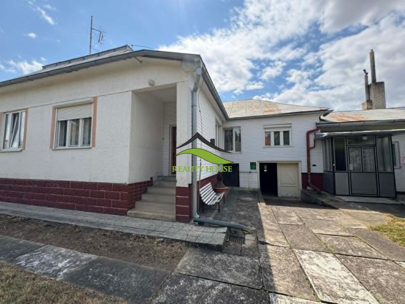 REZERVOVANÉ....Rodinný dom  v obci Dúbravka - Rodinný dom v Dúbravke so schodiskom, dvorom a garážovými dverami pod modrou oblohou.