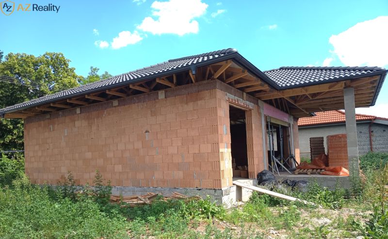 Na predaj novostavba v obci Andovce - Rodinný dom v Andovciach počas výstavby s tehlovými múrmi a tmavou strechou.
