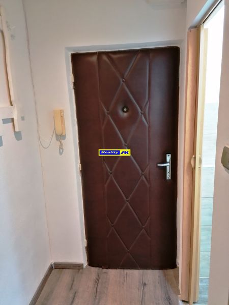 Garsónka na prenájom Vrútky, kompletná rekonštrukcia - Dvere v garsónke s telefónom na stene a laminátovou podlahou.