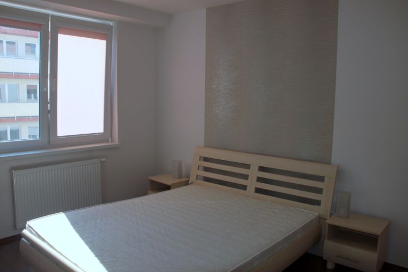 PRENÁJOM: SLNEČNÝ 3 IZBOVÝ BYT S BALKÓNOM A PARKOVANÍM, CENTRUM - Spálňa v 3-izbovom byte s posteľou, svetlými stenami a podlahou s dreveným dekorom.