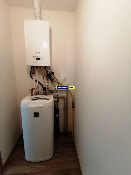 Rodinný dom novostavba na predaj Kláštor pod Znievom  - Kombinovaný bojler s potrubím v technickej miestnosti rodinného domu, podlaha s dreveným dekorom.