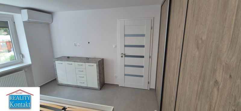 Na prenájom kompletne prerob. NOVÝ 2 izbový byt čiast.zar. Nové Zámky - Svetlý interiér 2-izbového bytu s komodou a bielymi dverami, podlaha s dreveným dekorom.