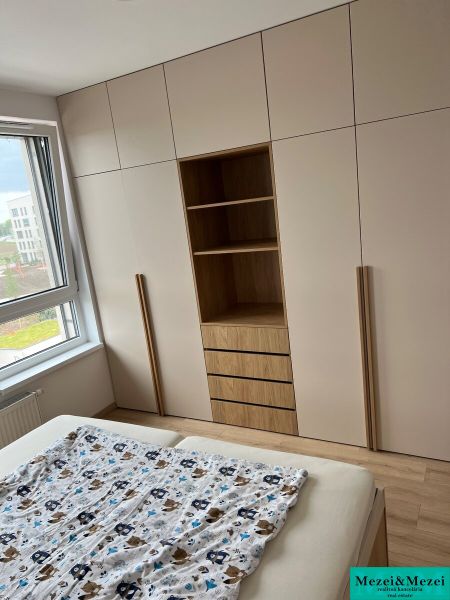 Kompletne zariadený 3-izbový byt s balkónom | PRÚDY Trnava - Spálňa v 3-izbovom byte s veľkou vstavanou skriňou a podlahou s dreveným dekorom.