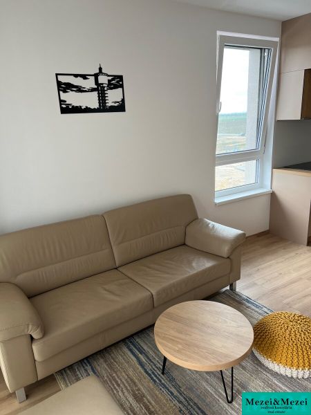 Kompletne zariadený 3-izbový byt s balkónom | PRÚDY Trnava - Obývacia miestnosť s koženou sedačkou, podlahou s dreveným dekorom a oknom.