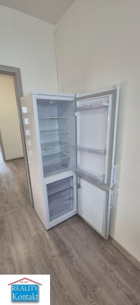 Na prenájom kompletne prerob. NOVÝ 1 izbový byt čiast.zar. Nové Zámky - Otvorená chladnička na podlahe s dreveným dekorom v 1-izbovom byte.