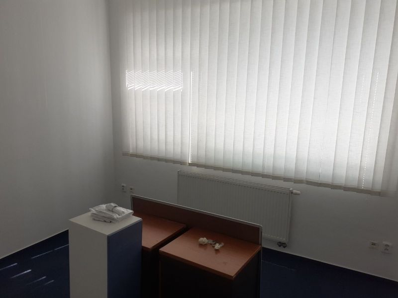 Klimatizovaná 2 - kancelária 25 m2 (12,5 m2 + 12,5 m2) na Pluhovej ul. - Prázdna kancelária s vertikálnymi žalúziami a stoly s prihradenými úložnými priestormi.