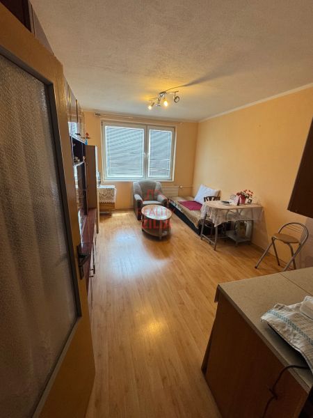 Na predaj Garsônka, 24,5 m2, s perfektnou polohou.  - Garsónka s podlahou s dreveným dekorom, jedálenským stolom a kreslami.