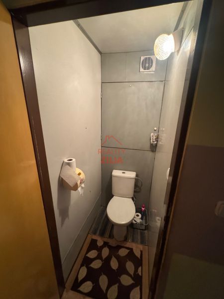 Na predaj Garsônka, 24,5 m2, s perfektnou polohou.  - Toaleta v garsónke s dekoratívnym koberčekom a stenovým ventilátorom.