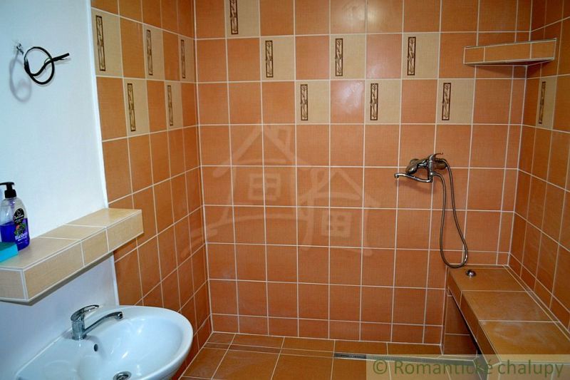 Dom so zrekonštruovaným interiérom - Varadka - Kúpeľňa v rodinnom dome s oranžovými obkladačkami a bielym umývadlom.