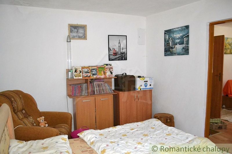 Dom so zrekonštruovaným interiérom - Varadka - Izba v rodinnom dome so sedačkou, komodou a dekoráciami, svetlá stena.
