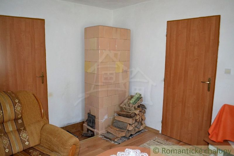 Dom so zrekonštruovaným interiérom - Varadka - Izba v rodinnom dome s kachľovou pecou a podlahou s dreveným dekorom.