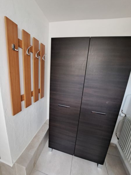 Prenajmeme garsónku, 27 m2, Melek, okr. Nitra - V garsónke sú tmavá skriňa, vešiaky a svetlá dlažba.