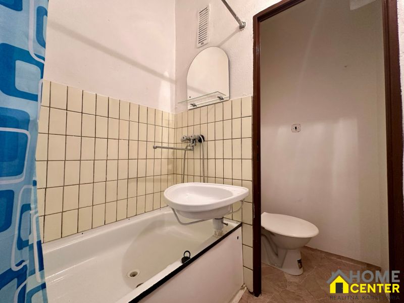 NA PREDAJ GARSÓNKA NA VII. SÍDLISKU, UL. BUBNOVÁ, KOMÁRNO - Kúpeľňa v garsónke s vaňou, umývadlom a závesom s modrým dekorom.