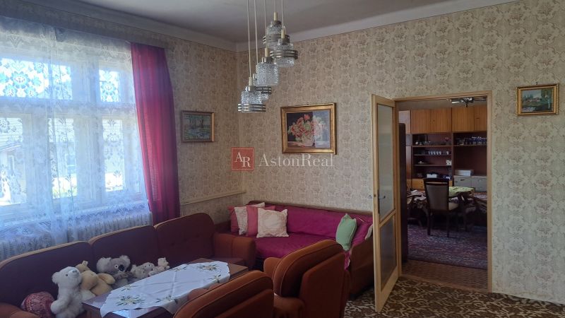 GAZDOVSKÝ DOM so záhradou a humnom, Ostrá Lúka pri Zvolene - Rodinný dom so starším nábytkom, vzorovanou tapetou a hračkami na pohovke.