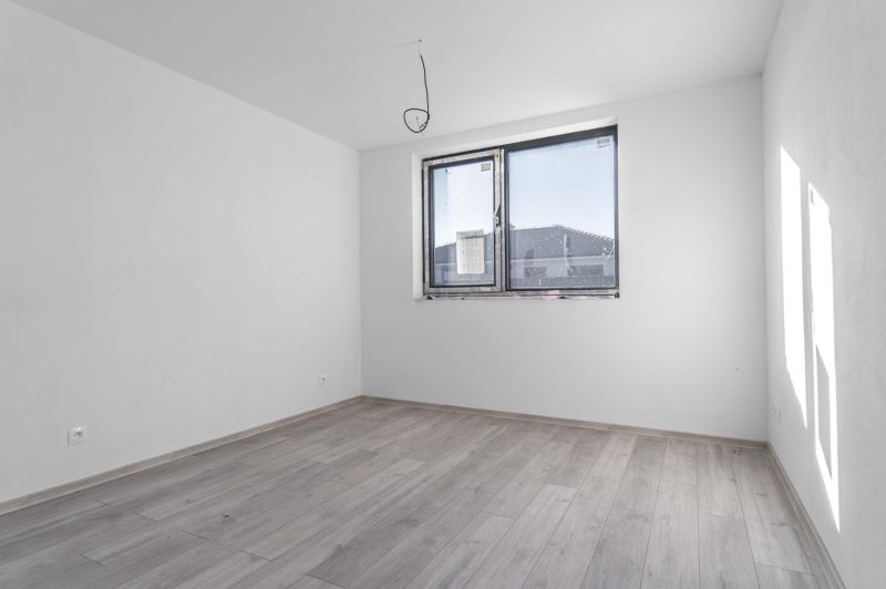 Na predaj nový moderný 4-izbový rodinný dom s terasou a záhradou - Prázdna izba v rodinnom dome s oknom a podlahou s dreveným dekorom.