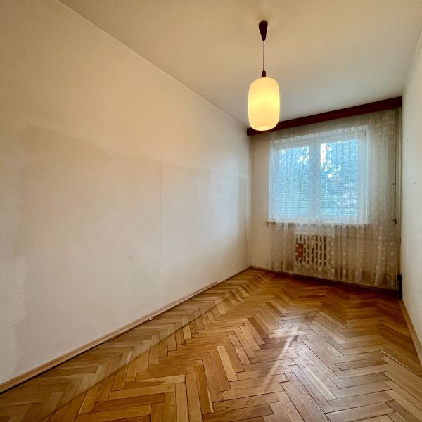 3-izbový byt s veľkou loggiou - Izba s bielymi stenami, visiaca lampa a podlaha s dreveným dekorom.