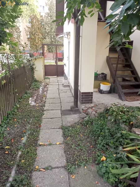 2 budovy v centre Komárna na predaj! - Chodník vedľa rodinného domu v Komárne, vedúci k vstupnej bráne, obklopený zeleňou.