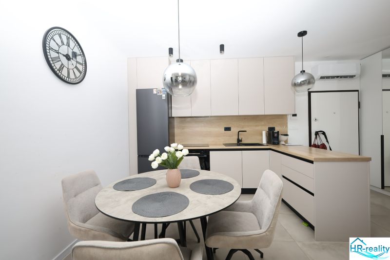 Chorvátsko, Vodice - zariadený apartmán s výhľadom na more - Kuchyňa v rekreačnom apartmáne s okrúhlym stolom a svetlým nábytkom.