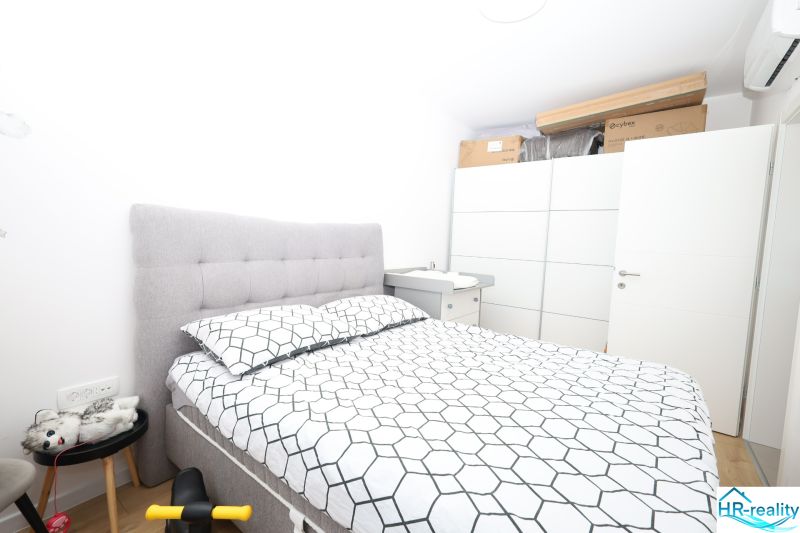 Chorvátsko, Vodice - zariadený apartmán s výhľadom na more - Spálňa v rekreačnom apartmáne s posteľou, nočným stolíkom a úložnými priestormi.