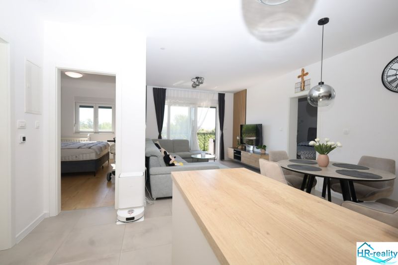 Chorvátsko, Vodice - zariadený apartmán s výhľadom na more - Obývačka v rekreačnom apartmáne s jedálenským stolom, gaučom a televízorom.