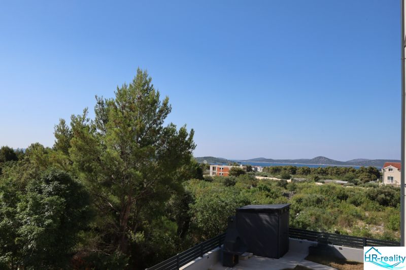 Chorvátsko, Vodice - zariadený apartmán s výhľadom na more - Výhľad z rekreačného apartmánu vo Vodiciach na stromy a Jadranské more.