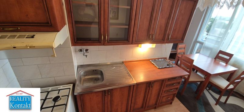 Na predaj 2 izbový byt 62m2 s 3 balkónmi - Nové Zámky  - Kuchyňa v 2-izbovom byte s drevenými kuchynskými skrinkami a jedálenským stolom.