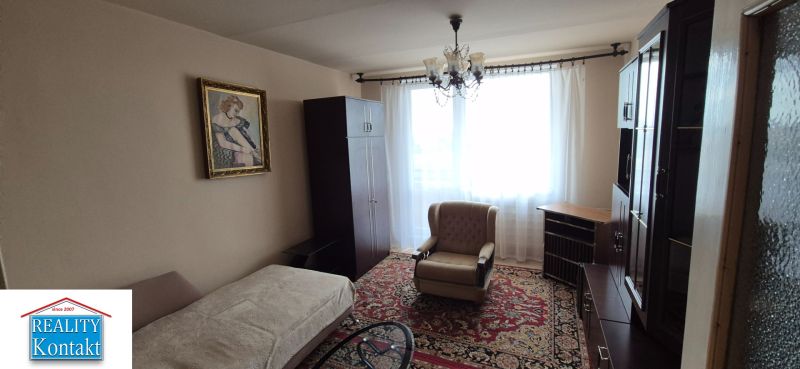 Na predaj 2 izbový byt 62m2 s 3 balkónmi - Nové Zámky  - Obývacia izba v 2-izbovom byte s kreslom, obrazom a záclonami.