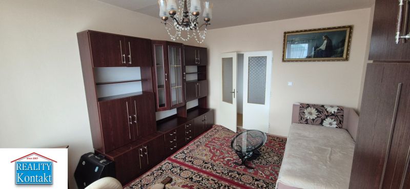 Na predaj 2 izbový byt 62m2 s 3 balkónmi - Nové Zámky  - Obývacia izba v 2-izbovom byte s dreveným nábytkom a kryštálovým lustrom.