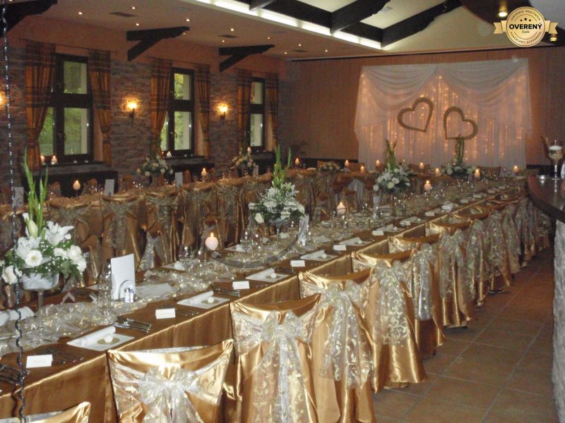 NA PREDAJ jedinečný gastro eventový areál v lesoparku Berek Nové Zámky - Gastro priestory s elegantnými dekoračnými stoličkami a svadobným stolom, podlaha s dreveným dekorom.
