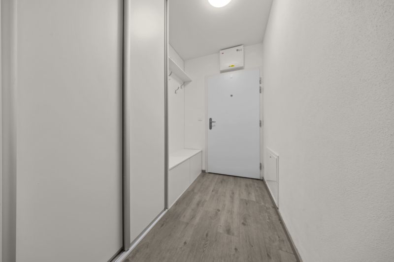 NA PREDAJ: 3-izbový apartmán, MATADORKA, Bratislava - Petržalka - Chodba 3-izbového bytu s bielou stenou, skriňou a podlahou s dreveným dekorom.