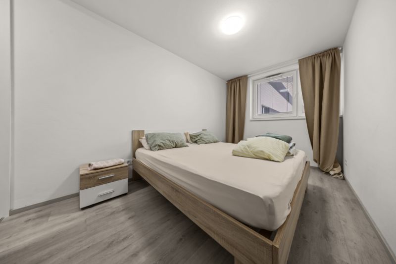 NA PREDAJ: 3-izbový apartmán, MATADORKA, Bratislava - Petržalka - Svetlá spálňa s posteľou a nočným stolíkom, podlaha s dreveným dekorom.