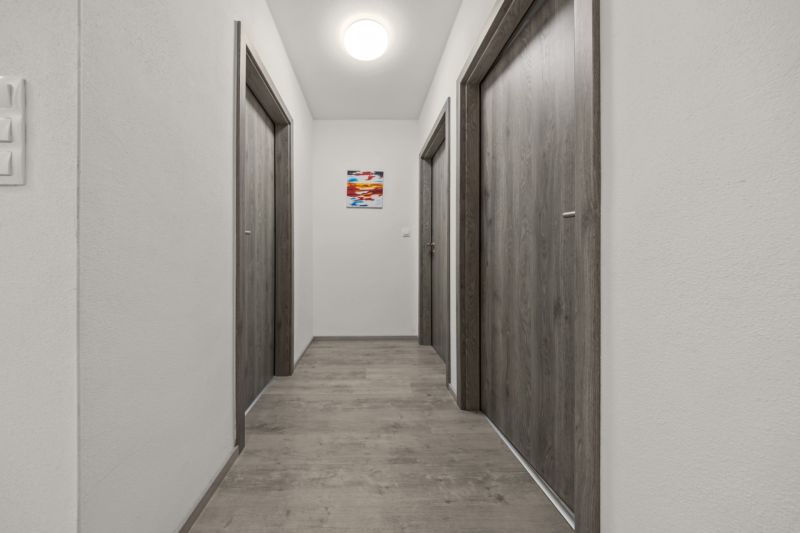 NA PREDAJ: 3-izbový apartmán, MATADORKA, Bratislava - Petržalka - Úzka chodba s podlahou s dreveným dekorom a tromi dverami v 3-izbovom byte.
