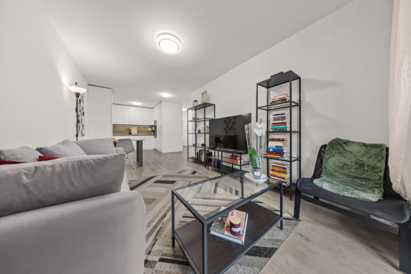 NA PREDAJ: 3-izbový apartmán, MATADORKA, Bratislava - Petržalka - Obývacia izba v 3-izbovom byte s gaučom, policami, sklom a podlahou s dreveným dekorom.