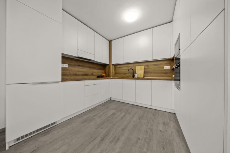 NA PREDAJ: 3-izbový apartmán, MATADORKA, Bratislava - Petržalka - Kuchyňa v 3-izbovom byte s bielymi skriňami, dreveným dekorom a LED osvetlením.