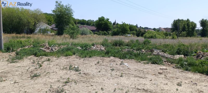 Na predaj investičný pozemok v obci Čechy - Pozemok na bývanie v Čechách so zeleňou a niekoľkými domami v pozadí.