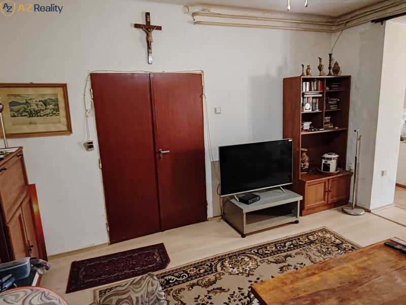 Rodinný dom na predaj Komárno - Obývacia izba v rodinnom dome s nábytkom a krížom na stene.