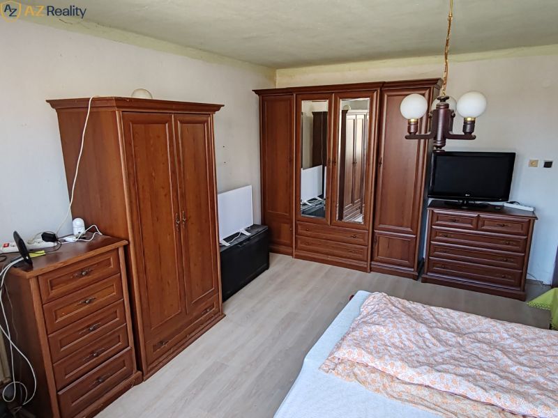 Rodinný dom na predaj Komárno - Spálňa s dreveným nábytkom, podlaha s dreveným dekorom, posteľ, skrine, lampa.